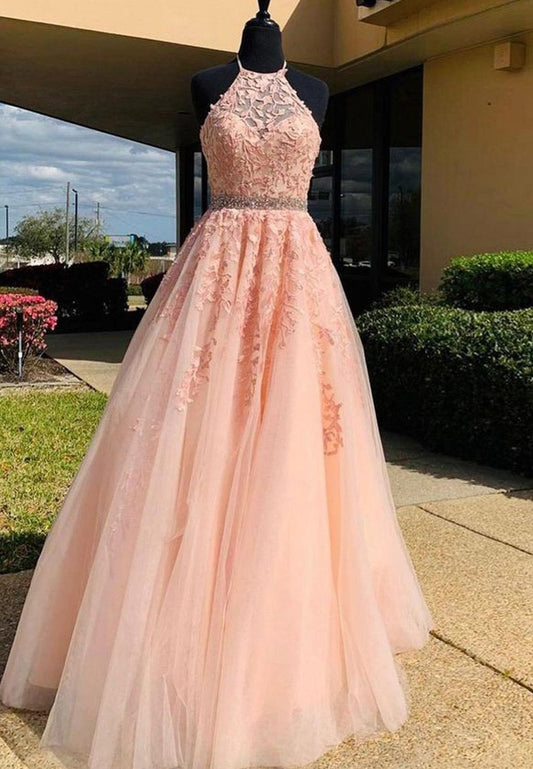 A pink, a-line tulle prom dress with applique and beaded details, displayed on a mannequin outside of a building.